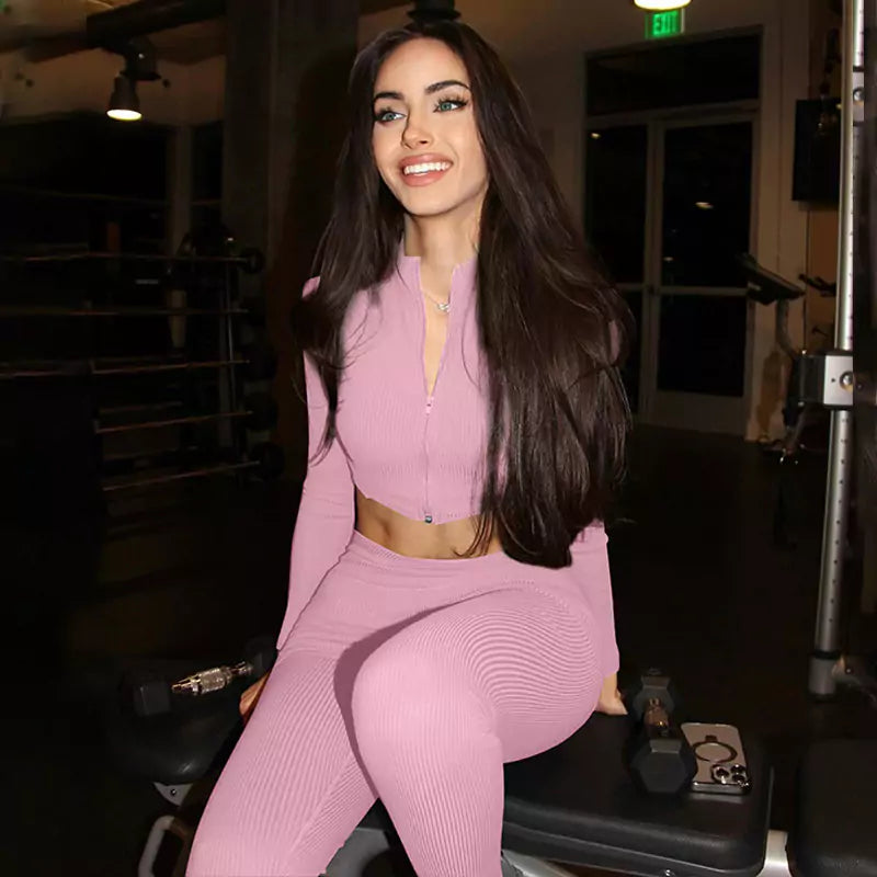 Woman in a pink outfit sitting on a weight bench in a gym.