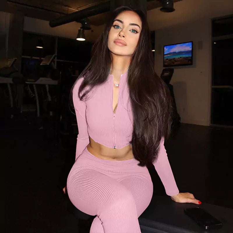 Woman in pink outfit sitting on a chair in a dimly lit room.
