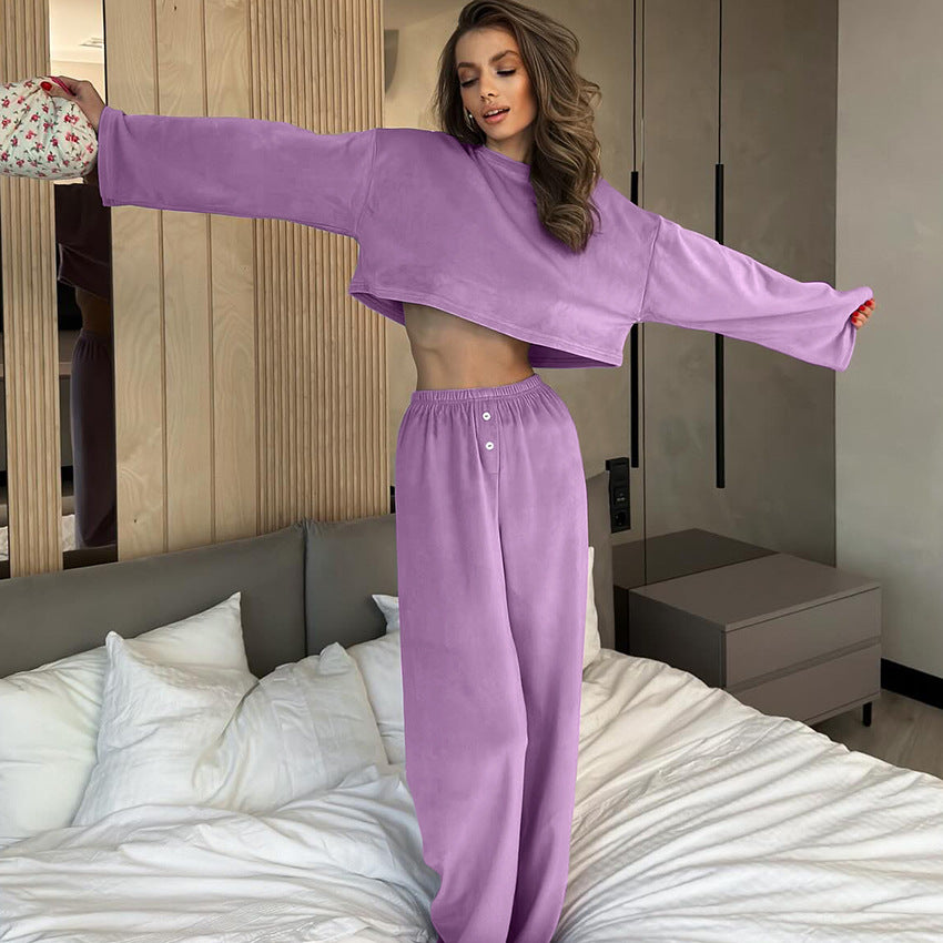 Woman in a purple outfit standing on a bed in a bedroom.