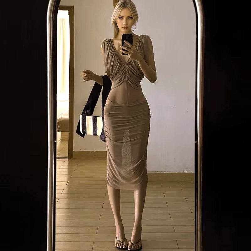 Woman taking a mirror selfie wearing a beige dress in a room.