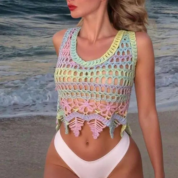 Woman wearing a colorful crochet top and white bottoms on a beach.